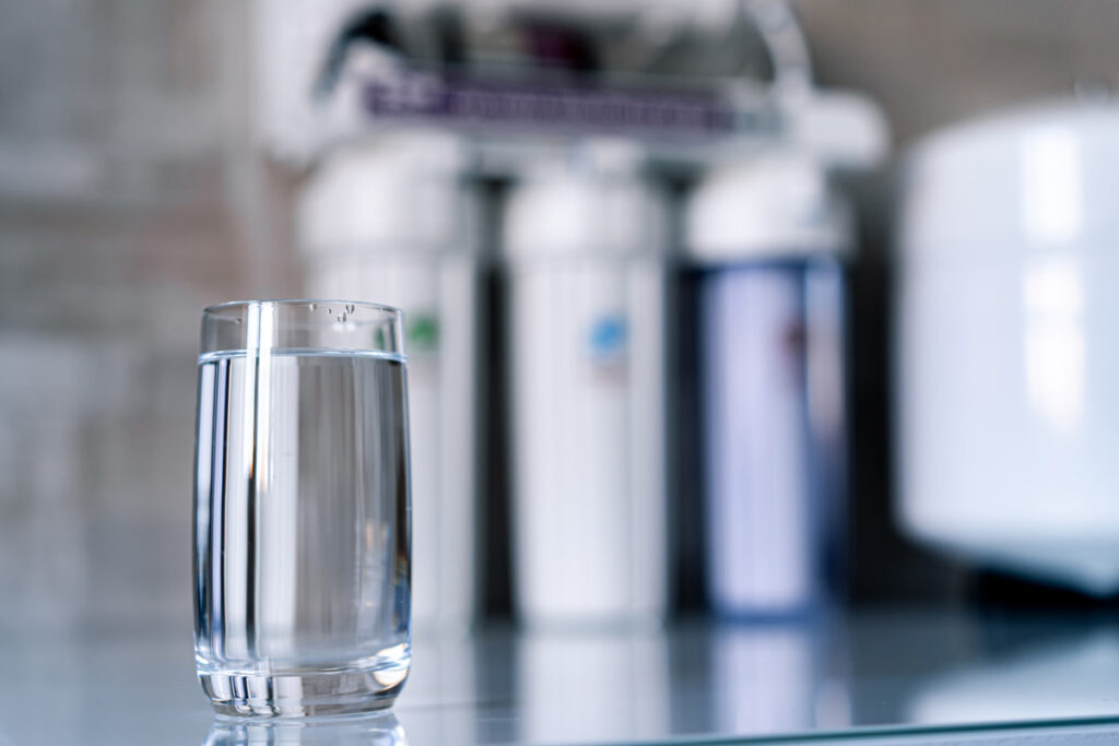 A glass of water in front of filters for a drinking water system in El Paso.