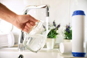 A person holding a glass vase under a faucet in El Paso.